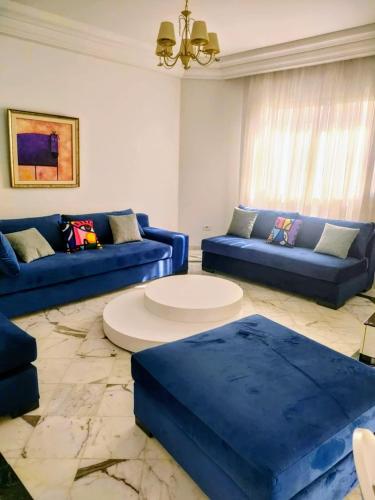 un salon avec des canapés bleus et une table dans l'établissement Appartement luxueux aux berges du lac 1, à Tunis