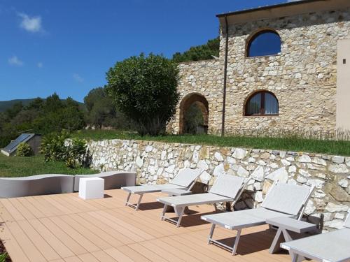 a group of white chairs and a stone wall at Poggio di Sole in Lacona