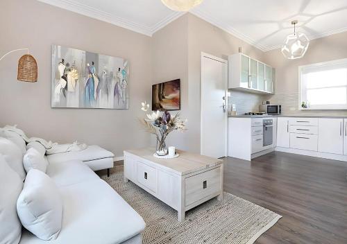 a white living room with a white couch and a table at Luxe Newly Renovated 2 Bed Unit - WALK TO BEACH in Wollongong