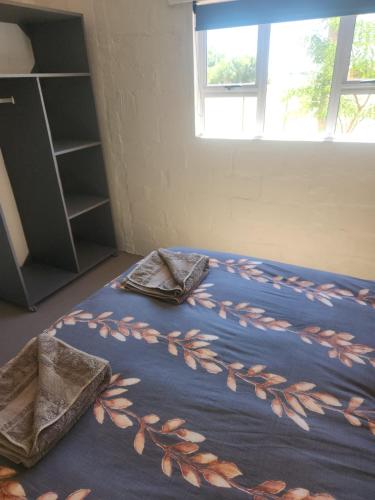 a bed with a blue blanket with leaves on it at Volgenoeg Self Catering Family Unit in Oudtshoorn