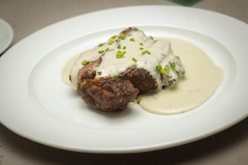 a piece of food on a white plate with sauce at Hotel Restaurant Les Brases in Sort