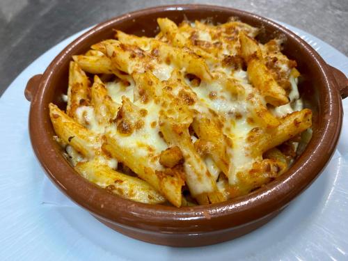 a bowl of pasta with cheese on a plate at Hotel Restaurant Les Brases in Sort