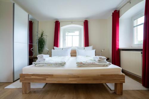 a bedroom with a large white bed with red curtains at Littehof - Ferienwohnungen in der Oberlausitz in Löbau