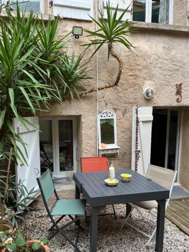 a black table and chairs in front of a house at Le Segarius superbe maison médiévale Internet WiFi gratuit Climatisation Jardin in Puisserguier