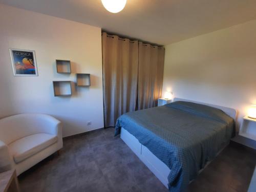 une chambre avec un lit, une chaise et des lumières dans l'établissement F2 Alata proche d'Ajaccio rez-de-villa, à Alata