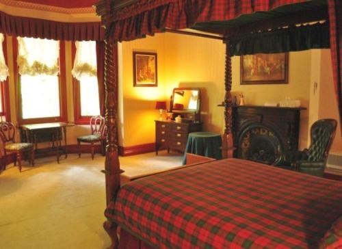 um quarto com uma cama com um cobertor xadrez vermelho em Ormiston House em Strahan