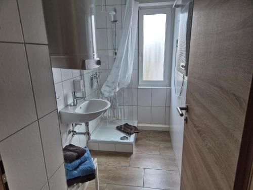 ein weißes Badezimmer mit Waschbecken und Fenster in der Unterkunft Ferienwohnung S-Bahn Nähe in Schwaikheim