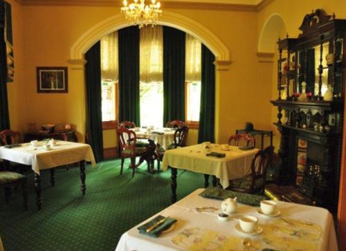 uma sala de jantar com duas mesas e um lustre em Ormiston House em Strahan