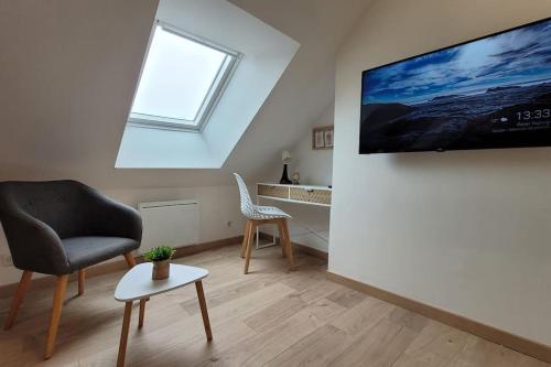 a living room with a chair and a tv on a wall at Le Perchoir - EasyEscale in Nogent-sur-Seine