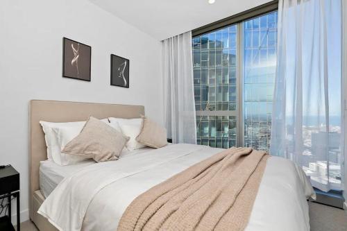 a bedroom with a white bed with a large window at Luxury apartment in Melbourne in Melbourne
