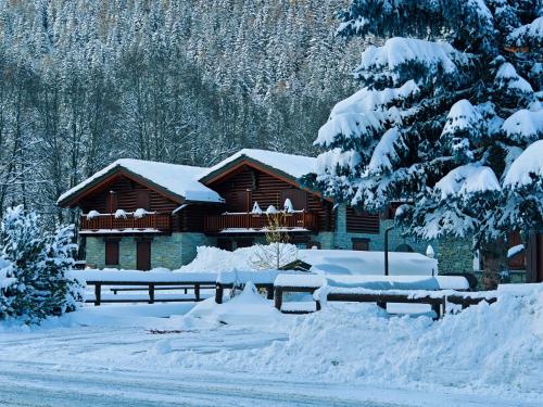 a log cabin in the snow with snow covered trees at Champoluc Apartment in Champoluc