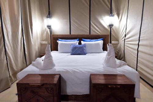 a bedroom with a large white bed with two tables at Dar Chams Ouarzazate in Ouarzazate
