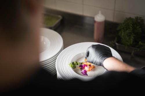 a person holding a plate with a doughnut on it at Boutique Pension Erlacher - Adults Only in Villandro