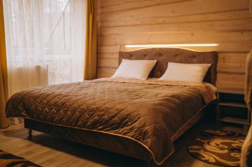 a bedroom with a bed with a wooden wall at SV HOTEL&camp in Lazeshchyna