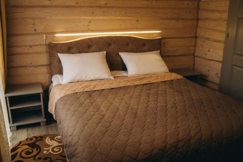 a bed with two pillows in a room with wooden walls at SV HOTEL&camp in Lazeshchyna