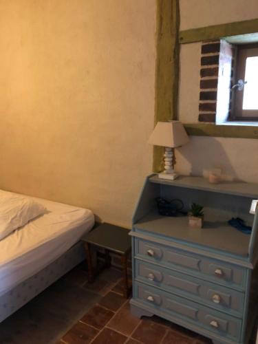 a bedroom with a bed and a blue dresser with a lamp at Petite maison paisible in Brillecourt