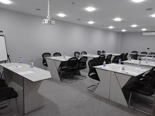 a conference room with white tables and black chairs at Alqalah Restotel فندق ومطعم القلعة in Kerak