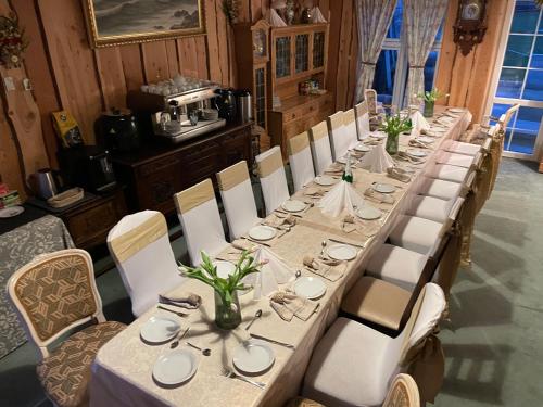a long table with white tables and chairs in a room at K&B Residence in Jarosław
