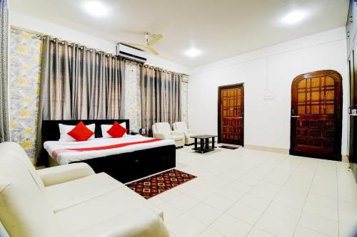 a bedroom with a bed and chairs in a room at Hotel O The Dove Villa in Dispur