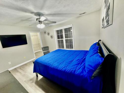 a bedroom with a blue bed and a ceiling fan at Haven Away From Home Ideal For Long Term Stays in Fayetteville