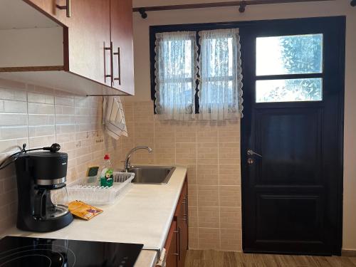 a kitchen with a black door and a sink at Genari Beach Apartments -Family sea view apartment in Korakokhórion
