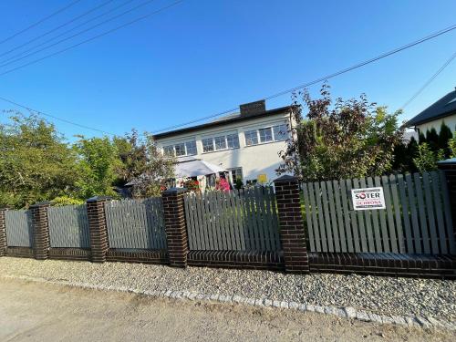 a fence in front of a house with a for sale sign at K&B Residence in Jarosław