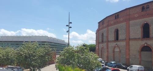 a large brick building with cars parked in a parking lot at Le Segarius superbe maison médiévale Internet WiFi gratuit Climatisation Jardin in Puisserguier