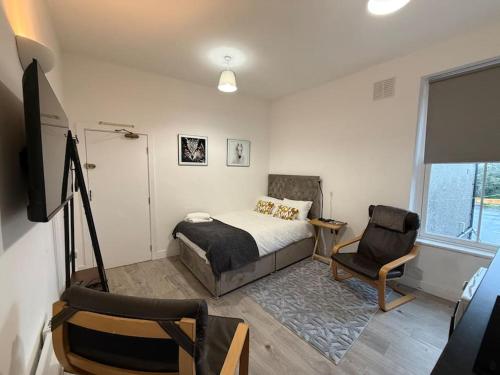 a bedroom with a bed and a tv and a chair at Cosy Studio Central Colwyn Bay F2 in Colwyn Bay
