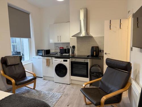 a kitchen with two chairs and a stove top oven at Cosy Studio Central Colwyn Bay F2 in Colwyn Bay