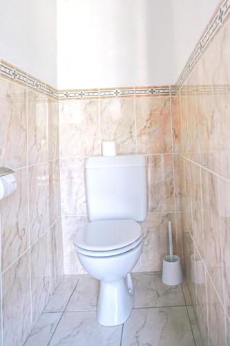 a white toilet in a bathroom with marble tiles at Hôtel Le Montaigu in Luz-Saint-Sauveur