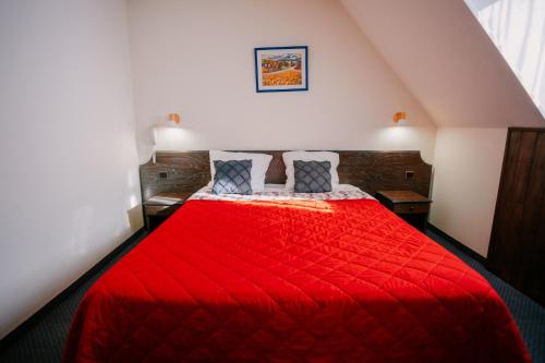 a bedroom with a red bed with two pillows at Hôtel Le Montaigu in Luz-Saint-Sauveur