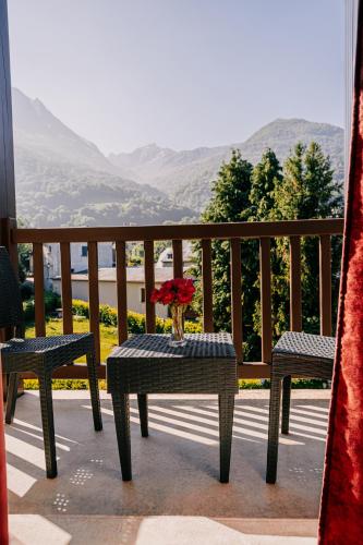 a table with a vase of flowers on a balcony at Hôtel Le Montaigu in Luz-Saint-Sauveur