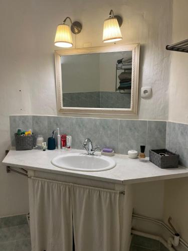 a bathroom sink with two lights and a mirror at Le Segarius superbe maison médiévale Internet WiFi gratuit Climatisation Jardin in Puisserguier