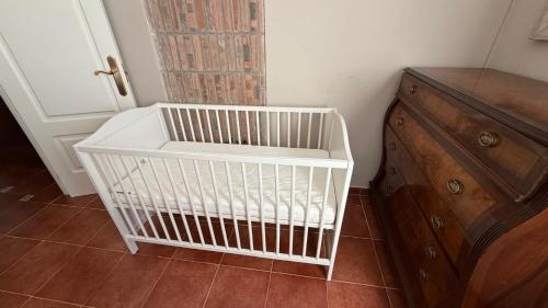a white crib sitting next to a wooden dresser at Torre Calera in Arganda del Rey