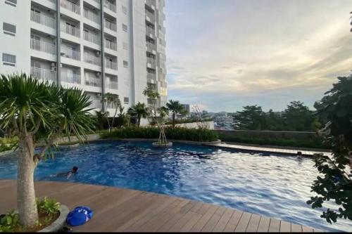 a man swimming in a swimming pool in front of a building at Comfortstay - Citra Plaza Nagoya #31-08 Sea View in Jodoh