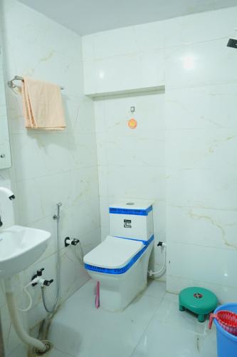 a white bathroom with a toilet and a sink at Walkinn Homestay Near TAJ MAHAL in Tājganj