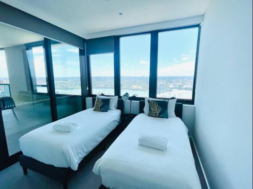 two beds in a room with large windows at Brand New Waterview family residence 3 bedrooms -Pool, Parking in Sydney