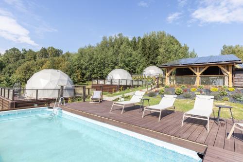 a swimming pool with chairs and a house with domes at Idea by Glamp in Wojcieszyce