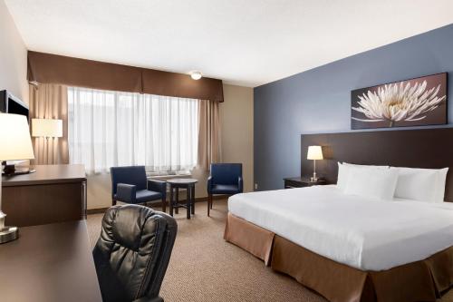 a hotel room with a bed and a desk and chair at Days Inn by Wyndham Montreal Airport Conference Centre in Dorval