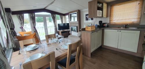 a kitchen and dining room with a dining table and a kitchen and a living room at Holiday Home at Combe Haven, St Leonards, Hastings in St. Leonards