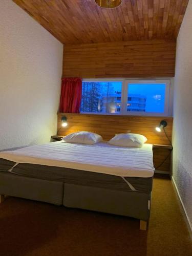 une chambre avec un grand lit avec une fenêtre dans l'établissement T3 aux Ecrins IV, skis aux pieds à Vars, à Vars