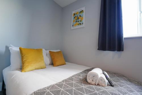 a bedroom with a bed with yellow and white pillows at En-Suite Rooms in Llanelli