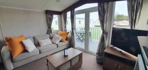 a living room with a couch and a flat screen tv at Holiday Home at Combe Haven, St Leonards, Hastings in St. Leonards