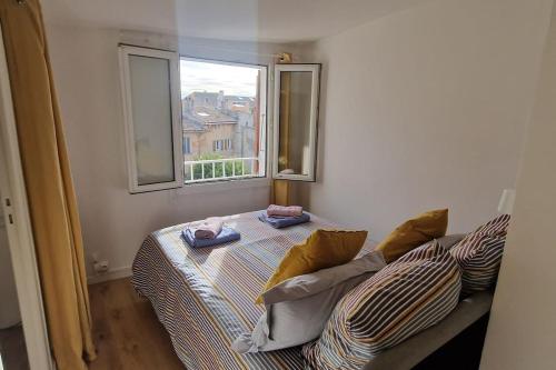 une chambre avec un lit avec des oreillers et une fenêtre dans l'établissement Cocon ensoleillé centre ville historique, Clim Wifi 4 people, à Aix-en-Provence