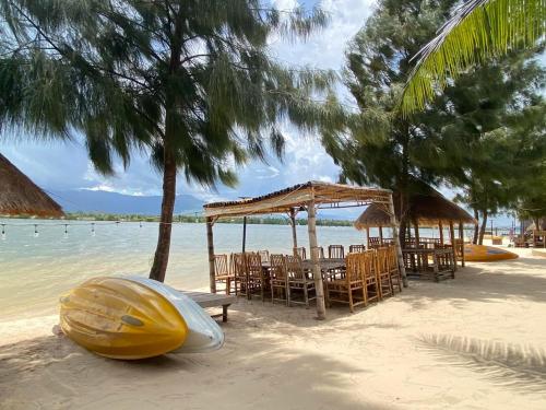 a boat laying on the beach with a table and chairs at Damboung Bungalow in Kampot