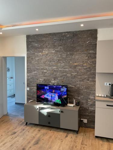 a living room with a tv and a brick wall at Apartman Magic house in Kruševac