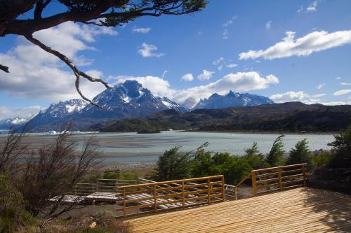 a wooden deck with a view of a lake and mountains at Hotel Lago Grey in Torres del Paine