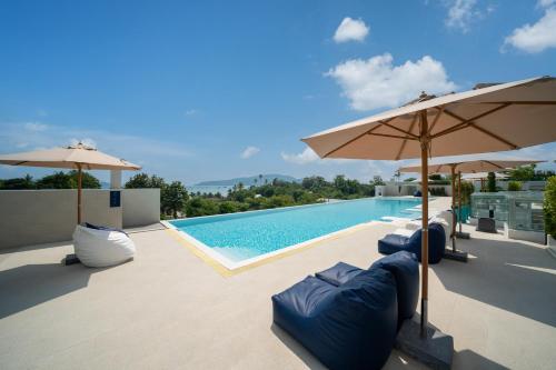 a swimming pool with umbrellas and loungers next to a swimming pool at Chalong Marina Bay View Rawai Phuket in Rawai Beach