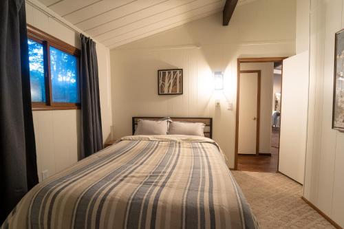 a bedroom with a bed with a striped comforter at Secluded Chalet near Ohiopyle and Seven Springs in Acme