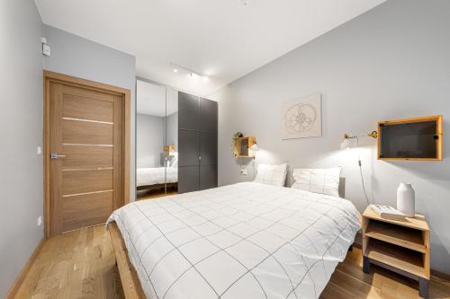 a white bedroom with a large bed and a television at Cozy 55m2 Zverynas Retreat with Lodge in Vilnius